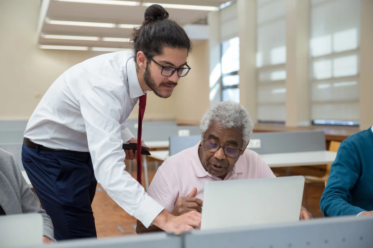 A technician helping an older man with his laptop